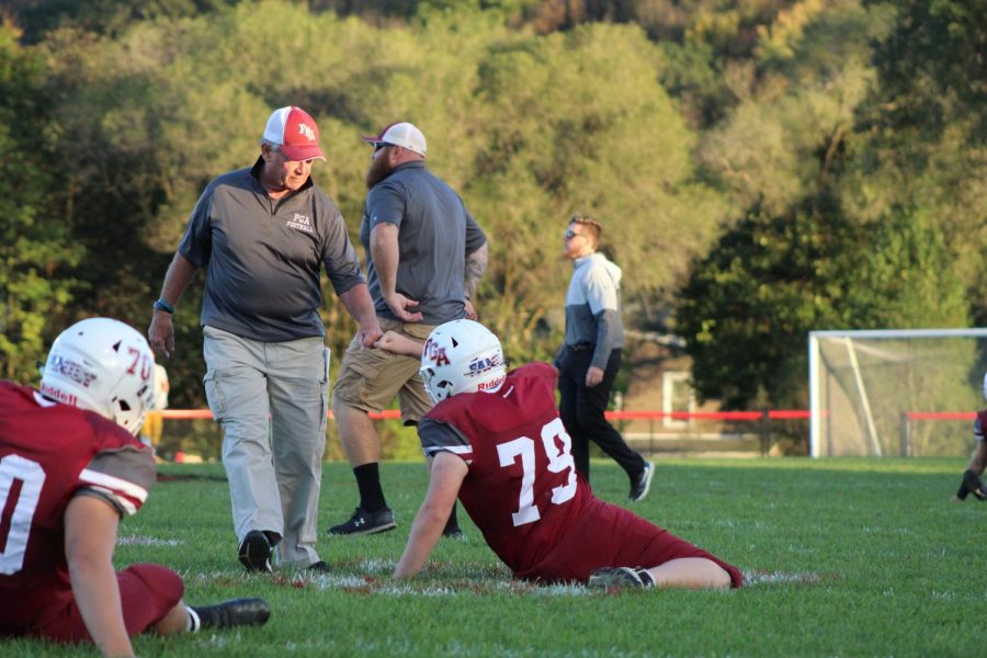Ty Reynolds stretching before the game, as Coach Tom Renninger gets him ready to play.