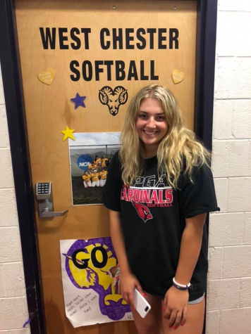 Trisha Kopinetz stands in front of her college softball team’s dorm room.