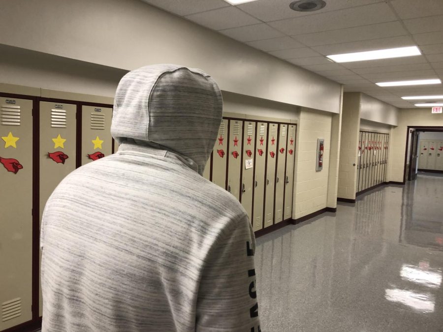 Student walking in the hallway with a hood up.