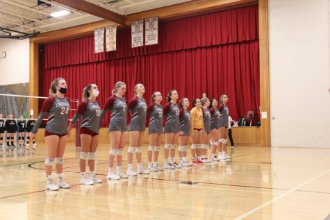 The girls volleyball team standing for the pledge. Seniors doing the wave in front of a home crowd for the last time. They were all focused on playing their hearts out for their seniors.