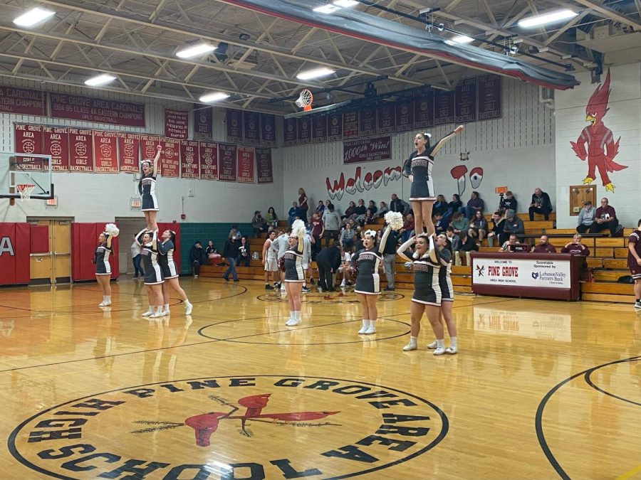 The girls at a boys basketball game doing a cheer during a full timeout. Emily Zimmerman ,junior, is flying on Katie Herring ,junior, and Taylor Wright ,sophomore, as a “ one man “ stunt. The second group is Kierah Harwi ,sophomore, flying on Fifetta Randazzo , freshman, and Kaitlyn Kauffman, sophomore.