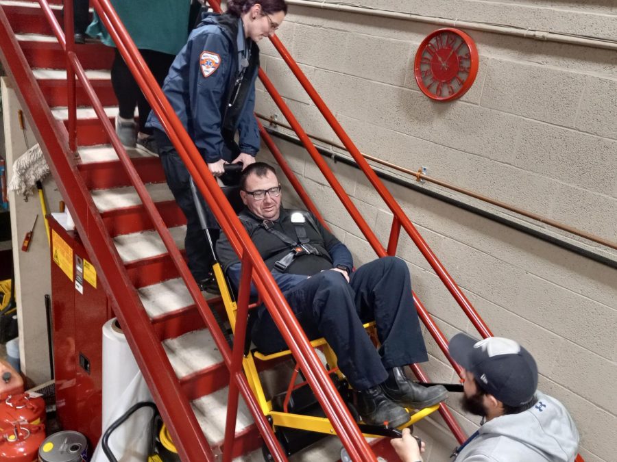 Ricky Ney sits in a stair chair device to train new EMTs in the proper use of it. The stair chair is used for getting immobile patients up and down stairs safely.