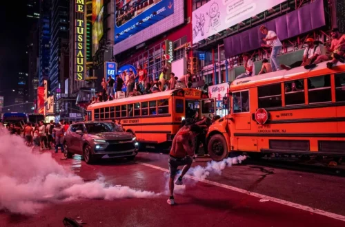 NYPD officers near crowds and damaged vehicles outside Madison Square Garden after a Knicks game